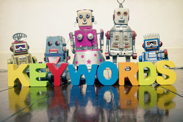 the word  KEYWORDS with wooden letters and retro toy robots  on an old wooden floor