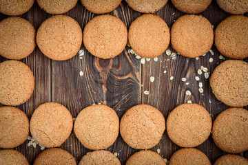 Homemade oatmeal cookies with raisins, cinnamon with milk on dark wooden background.