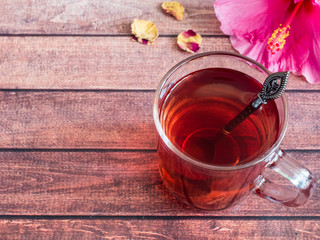 Glass Cup with red tea pink hibiscus flower on dark wood background