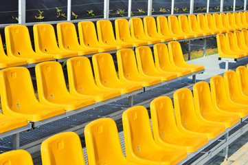 Żółte plastikowe krzesełka na trybunie stadionu sportowego. - obrazy, fototapety, plakaty