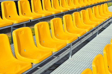 Żółte plastikowe krzesełka na trybunie stadionu sportowego. - obrazy, fototapety, plakaty