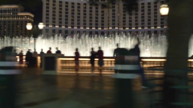 Las Vegas strip driving shot at night. Car drives near famous fountain show in Las Vegas. Blurred out of focus video. Background video.