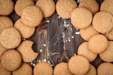 Homemade oatmeal cookies with raisins, nuts with milk on dark wooden background.