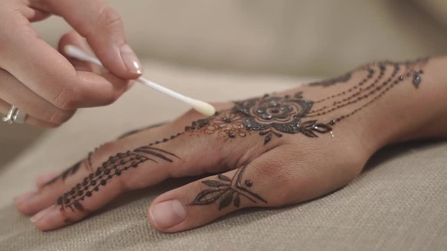 close up shot of the woman's hands, the master spa salon applies protective oil on the finished mehendi, a variety of patterns look elegant and beautiful on young skin