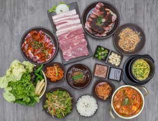 Table of set of korean barbecue, pork, meat, rice, vegetables, sauce and hood