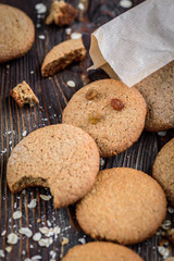 Homemade oatmeal cookies with raisins, cinnamon with milk on dark wooden background.