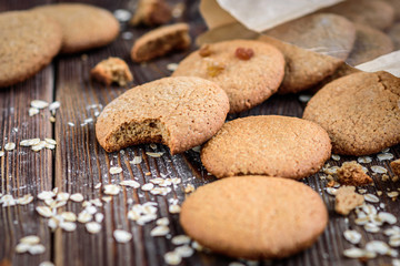 Homemade oatmeal cookies with raisins, cinnamon with milk on dark wooden background.