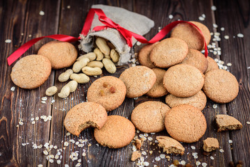 Homemade oatmeal cookies with raisins, cinnamon with milk on dark wooden background.