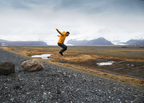 tourist jumps over rocks in Iceland
