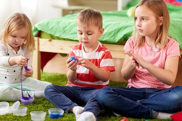 childhood, leisure and people concept - group of kids with modelling clay or slimes at home