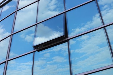Reflection of the blue sky in a glass building with an open window