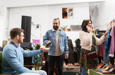 sale, shopping, fashion and people concept - friends choosing clothes and footwear at vintage clothing store