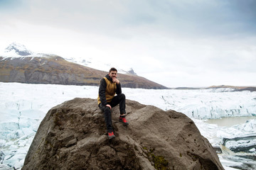 tourist sits near the glacier iceberg in Iceland