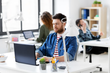 business, technology and people concept - creative man with laptop computer working at office