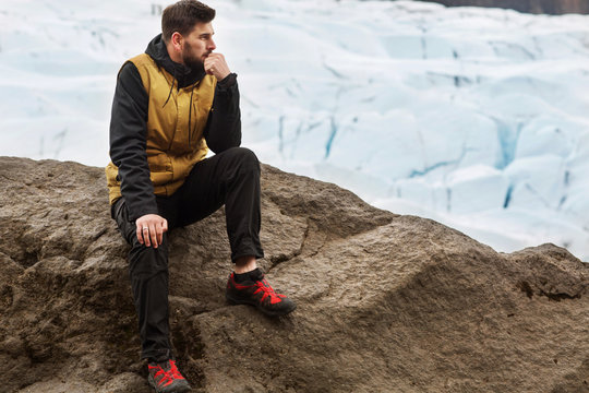 tourist sits near the glacier iceberg in Iceland