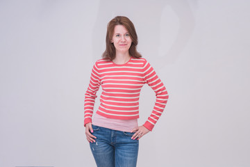 portrait of a beautiful brunette girl in jeans on a white background in different poses with different emotions.