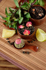 Blossom tea ball and leaf tea with rose petals in wooden cups and spoon