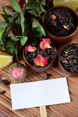 Different sorts of tea, mint and dry rose petals and a white card for a text