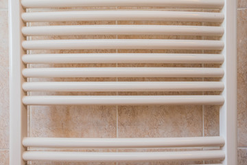 Close up of a modern white bathroom heater on wall with tiles. Bathroom hydraulic equipment.