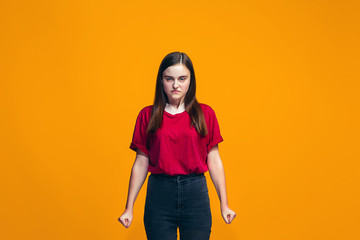 Portrait of angry teen girl on a orange studio background