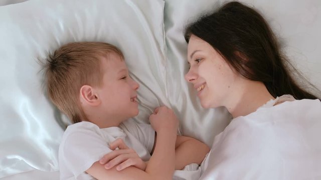 Mom and son wake up. Mom kisses and hugs her son.