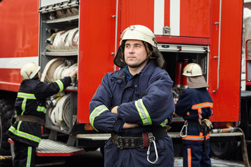 Fireman (firefighter) in action standing  near a firetruck. Emergency safety. Protection, rescue from danger.