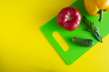 Vegetables on the green cutting board  on the yellow background.Top view.