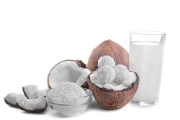 half coconut with coconut sweets, shavings and coconut milk on a white background isolated