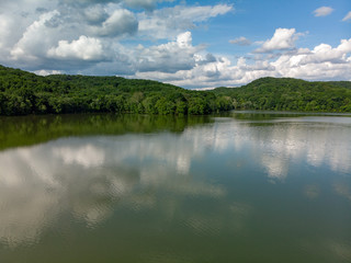 Aerial Forest Mountains On Reflective Lake with Cloudy Sky