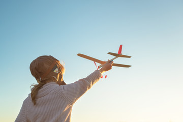 Girl in aviator hat playing pilot with toy plane outside © Nuli_k