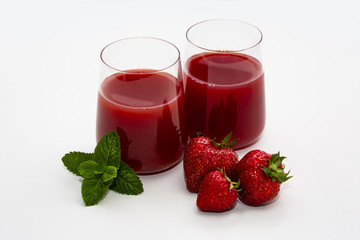 Two glasses with juice, strawberry and mint on a white background.