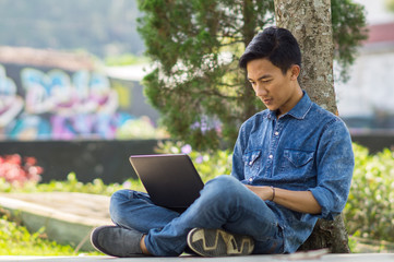 Asian young  man using computer outdoor