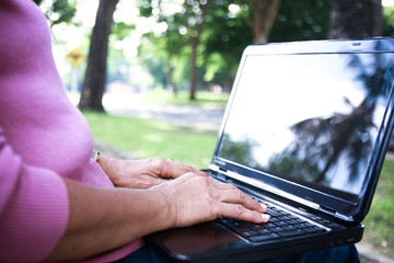 The elderly use a notebook computer to communicate in the garden.