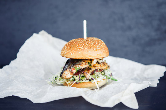 Freshmade streetfood fishburger on the butter-paper on the black background