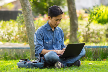 Asian young  man using computer outdoor