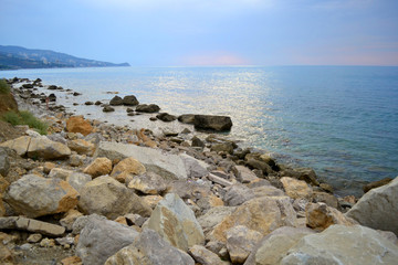 gray sea with rocks on the Beach and pink horizon