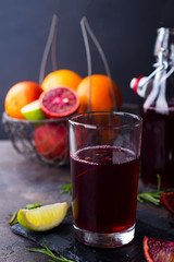 Summer berry juice in a glass with citrus on stone background