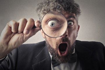 Surprised detective using a magnifier