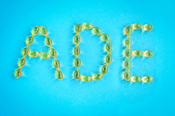 Yellow capsules forming shape to A, D and E alphabet on blue background