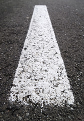 Raya de pintura blanca en asfalto de carretera.