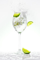 Fresh lime falling into a splashing sparkling water