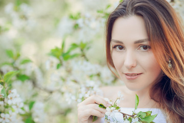 Fototapeta premium Young beautiful blonde woman in blooming almonds garden.