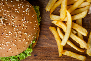 American burger and French fries on a wooden board. Photo from the top