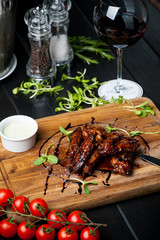 chicken wings baked on fire with mustard sauce, valerian, cherry tomatoes and cream sauce on a...
