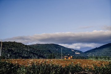 the farmer is driving across the field on a tractor against the backdrop of the mountains