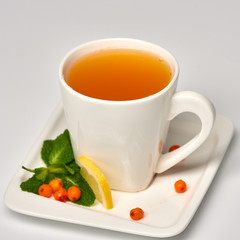 Cup of tea with sea buckthorn./Porcelain cup with sea buckthorn tea on white background.