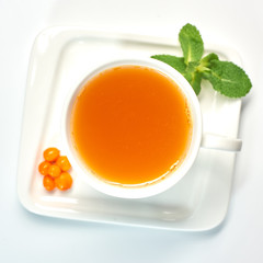Cup of tea with sea buckthorn./Porcelain cup with sea buckthorn tea on white background.