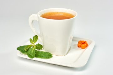 Cup of tea with sea buckthorn./Porcelain cup with sea buckthorn tea on white background.