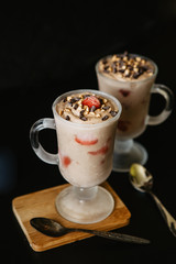 Homemade chocolate ice cream with strawberries in a glass on a black background
