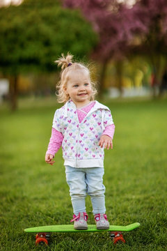 Funny baby with a skate in a Sunny Park.